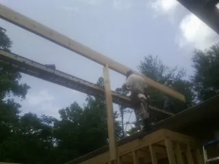 Carpenter setting a ridge beam over a new addition frame — Ice Dam Removal by Roofing Brothers in Pleasant Garden