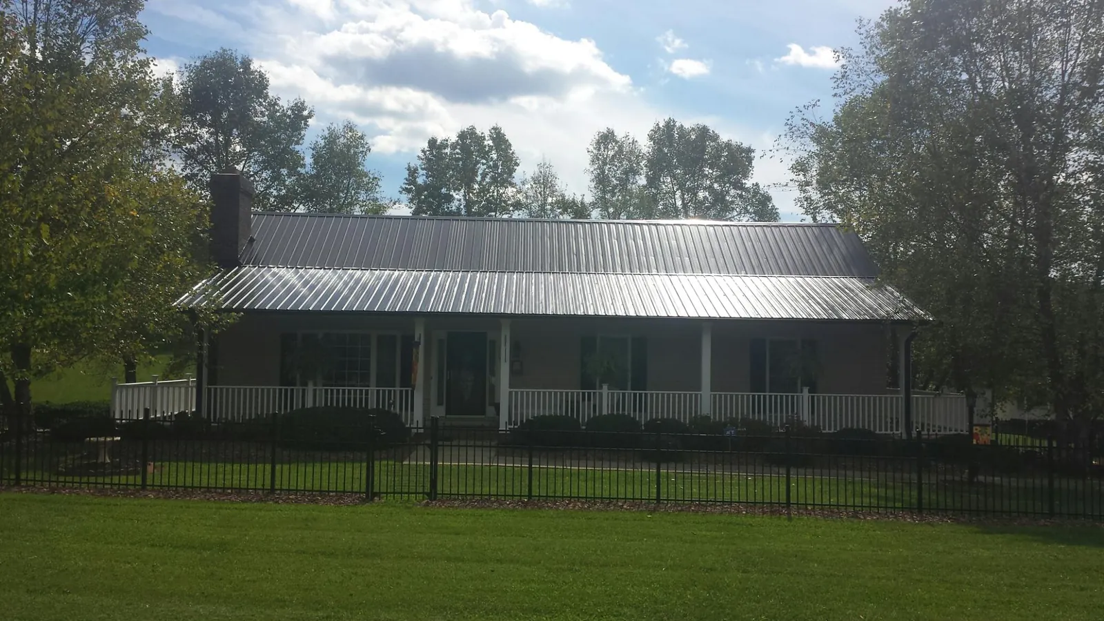 Gray metal roof on a brick ranch with a full width front porch — Gutter Guard Installation work by our crew in Pleasant Garden