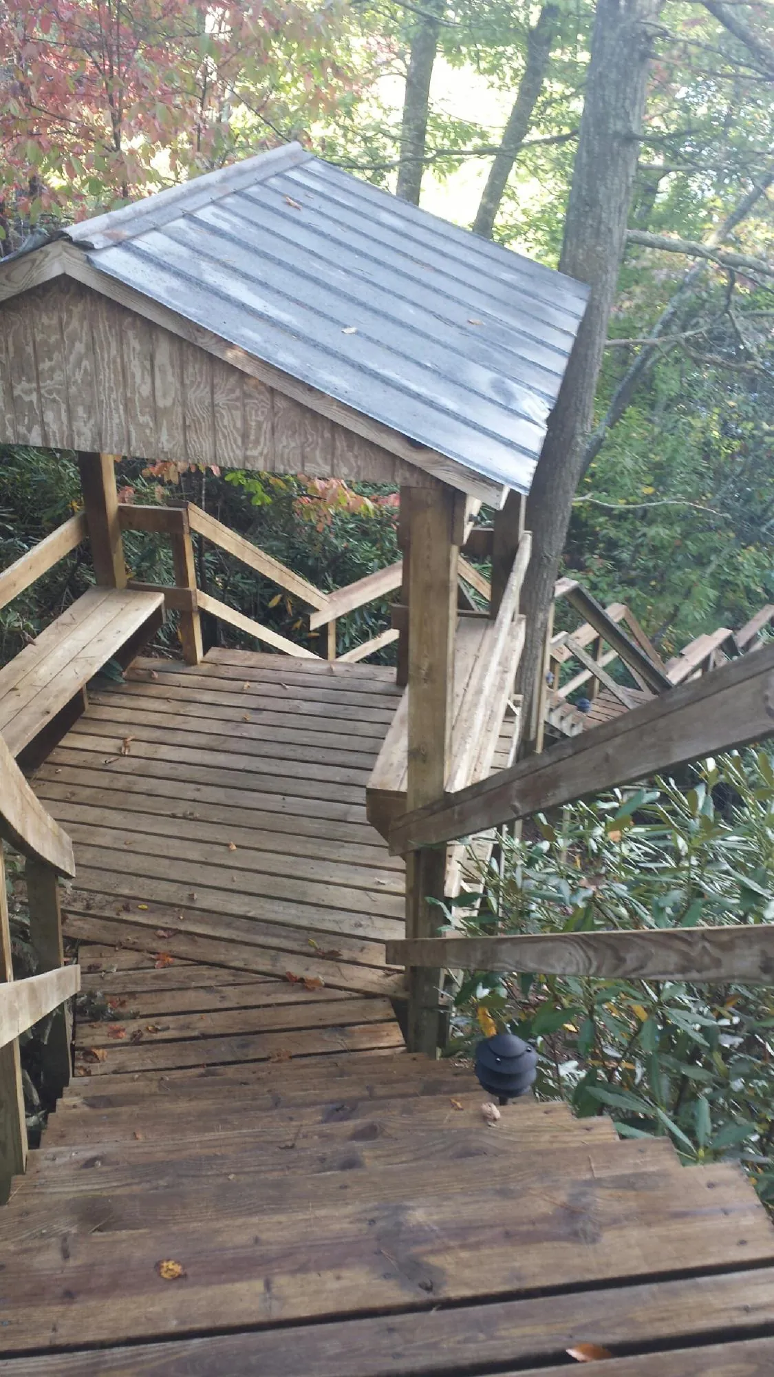 Metal roofed shelter over wooden steps on a wooded walkway — Skylight Repair & Installation work by our crew in Pleasant Garden