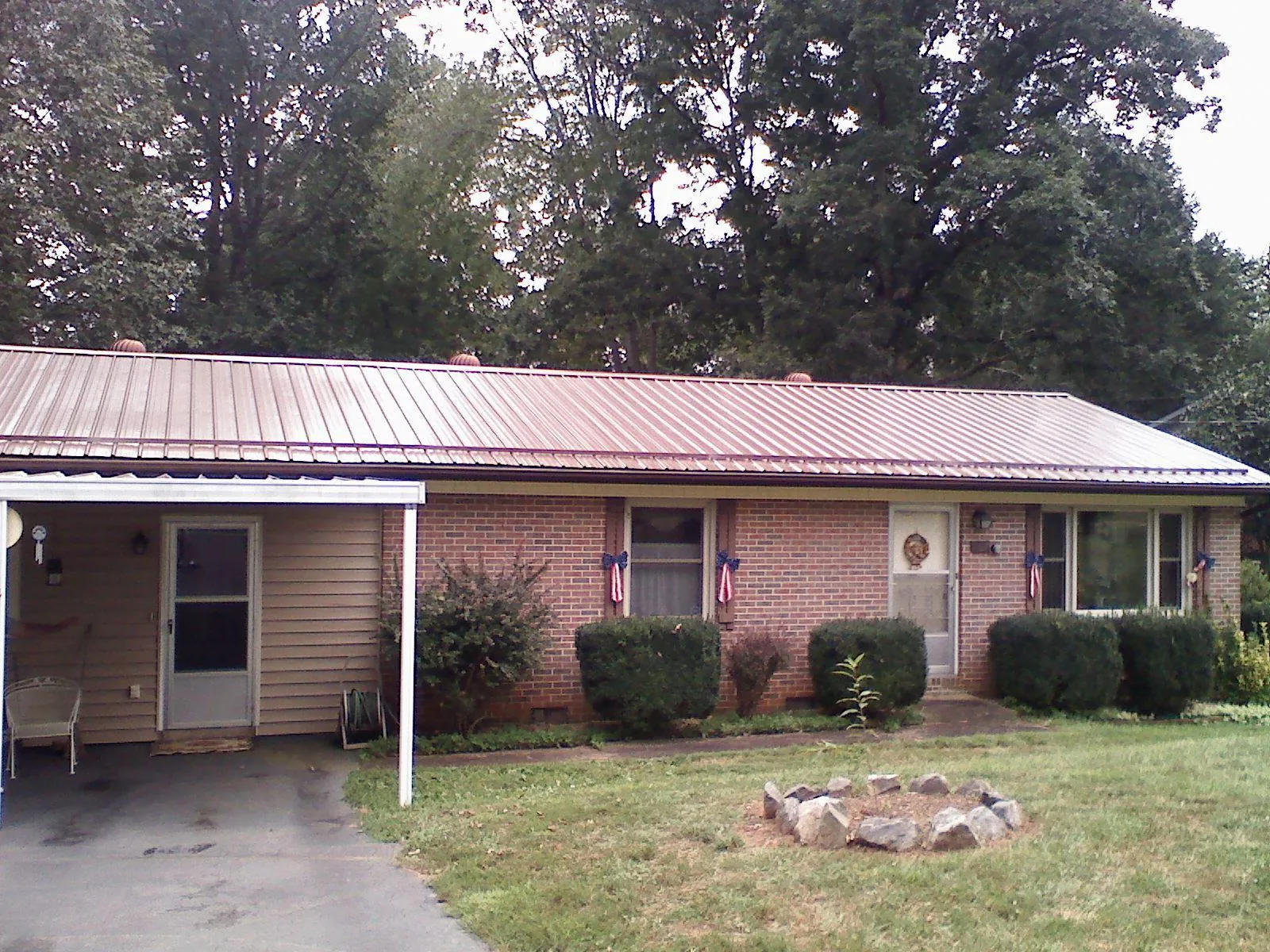 Bronze metal roof and carport on a brick ranch home — Roof Repair work by our crew in Pleasant Garden