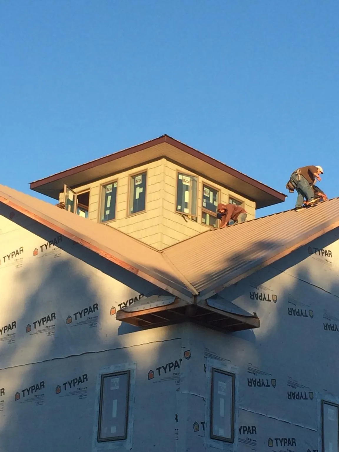 Roofers working around a rooftop cupola on a new metal roof at sunset — Roof Waterproofing in Pleasant Garden by Roofing Brothers